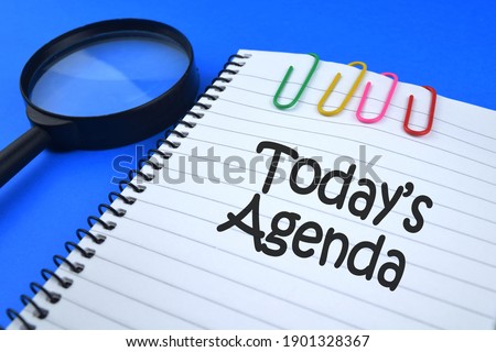 Selective focus image of magnifying glass with paper clips and Today's Agenda wording. Education and business concept.