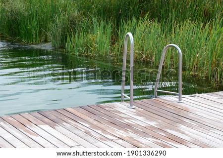 Natural pond of a natural swimming pool with wooden bridge and entrance - Natural swimming pool in South Tyrol