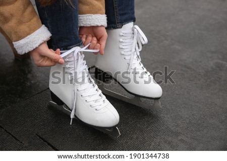Woman lacing figure skate outdoors, closeup view