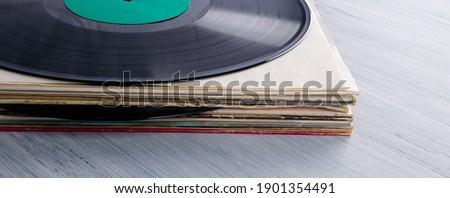 a stack of vinyl records in paper cases, on a gray table, background