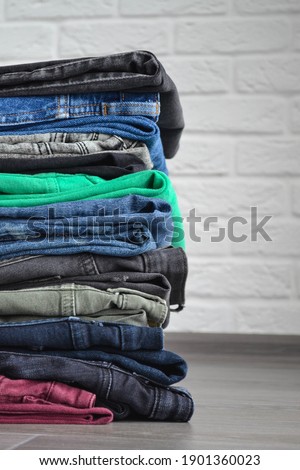 Jeans, clothing, denim. Detail of nice blue jeans vintage style. Denim texture or denim jeans background with old torn. Stock of jeans in different shades. The most comfortable clothes