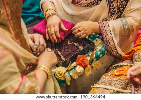 Senior women hands open velvet boxes with golden jewelry earrings for indian bride during wedding henna mehndi sangeet party night  Royalty-Free Stock Photo #1901366494