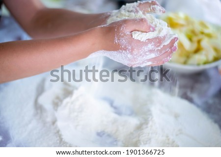 Handmade in the kitchen. Children's hands knead flour. Little helper in the kitchen. Home baking. Preparation of bread, pies and cakes. White flour on a brown silicone mat.