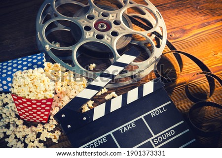 Cinema concept of vintage film reels, clapperboard and other tools on old wooden background.
