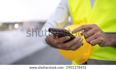 engineer working on his smart phone at the construction site Royalty-Free Stock Photo #1901378431