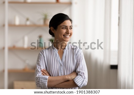 Successful millennial indian lady stand at home keep arms crossed on chest look at window with confident smile. Happy mixed race female private enterpreneur proud of being self made business woman Royalty-Free Stock Photo #1901388307