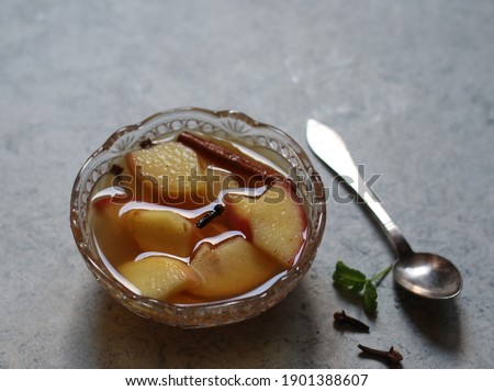 Hot mulled apple. made of slices apple, cloves, honey and cinnamon. served in small bowl on grey background. Selective focus