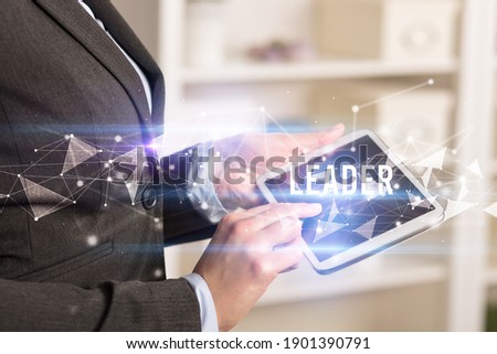 Close up hands using tablet with LEADER inscription, modern business technology concept