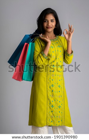 Beautiful young girl holding and posing with shopping bags on a grey background