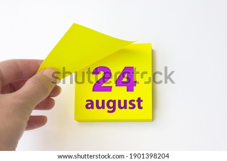 August 24th. Day 24 of month, Calendar date. Hand rips off the yellow sheet of the calendar. Summer month, day of the year concept