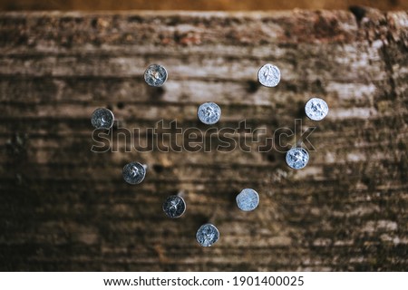 Into old wooden plank hammered nails in the shape of heart. Postcard for Valentine or Father Day. Business card for a hardware store, construction shop. I love you symbol. Stylish industrial concept.