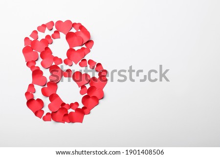 Number 8 made with red paper hearts on white background, top view. International Women's day