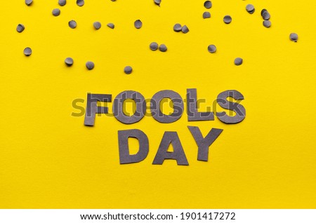 Image caption Fools' Day of carved paper letters of grey on a yellow background with grey confetti on the top edge. High quality photo