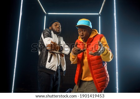Two stylish rappers poses in glowing cube