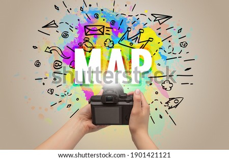 Close-up of a hand holding digital camera with abstract drawing and MAP inscription