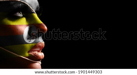 Uganda flag painted on a face of a young woman, national flag on face
