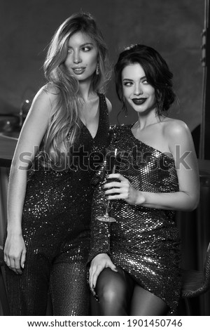 Two girls having fun in bar. Elegant woman in fahionable sequins dresses. Nightclub party. Female celebrating, having fun in bar. Beautiful caucasian blonde and brunette ladies