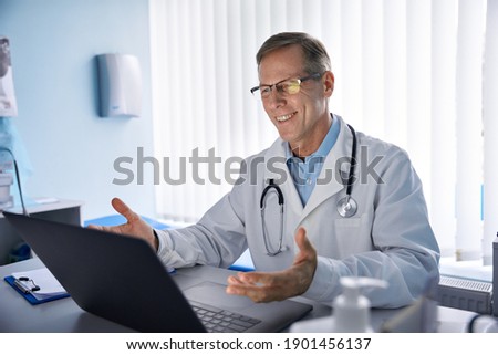 Happy old male doctor physician talking, consulting patient online by webcam video call on laptop computer. Telemedicine conference virtual tele meeting. E appointment, telehealth zoom therapy. Royalty-Free Stock Photo #1901456137