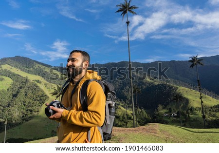 young man traveler looks to the horizon to take a picture of a beautiful landscape. traveling alone