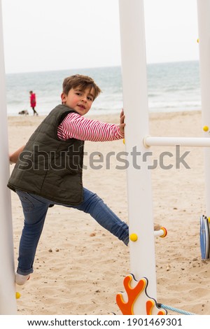 child playing on beach swing in winter clothes