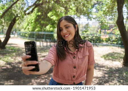 A beautiful Latin woman close up looking straight ahead in a city park                  