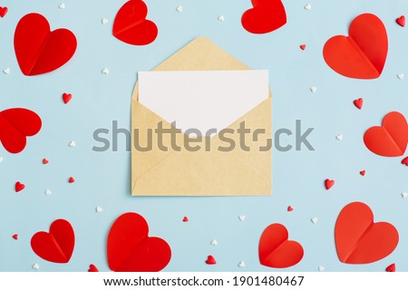 Valentine's Day background February 14th. Blank greeting card mock-up scene, confetti, red hearts of paper on pastel blue background. Valentines day concept. Flat lay, top view, copy space