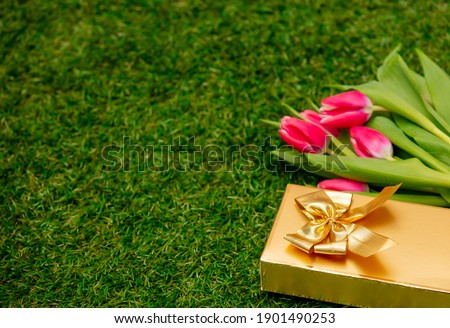 Gift box with a tulips on green grass in a garden