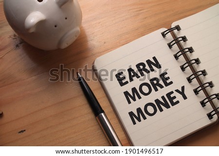 Earn more money, text words typography written on book against wooden background, life and business motivational inspirational concept