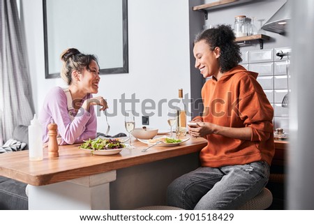 Our weekend. Waist up portrait view of the happy couple of friends sitting at the bar counter and laughing while having dinner at the kitchen. Friendship concept. Stock photo