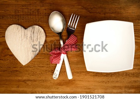 Fork, spoon,wooden heart. Celebrate valentines day. empty square white plate. 