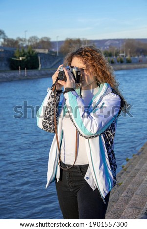 Woman taking photos with vintage camera next to river on a sunny day
