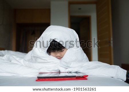 kid watching tablet on the bed, child addicted cartoon