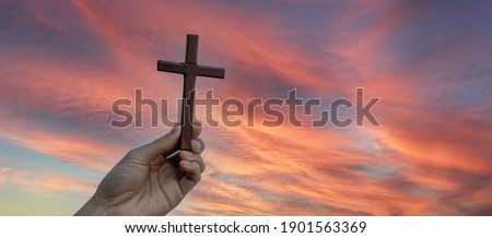 Silhouette hand holding wood cross against sunrise background, open palm up worship, pray for blessings from God. Christian Religion, Crucifix and Faith concept