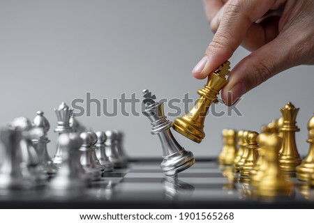 businessman hand moving gold Chess King figure and Checkmate enermy or opponent during chessboard competition. Strategy, Success, management, business planning, interruption and leadership concept Royalty-Free Stock Photo #1901565268