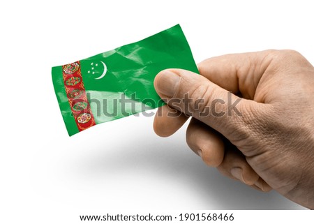 Hand holding a card with a national flag the Turkmenistan