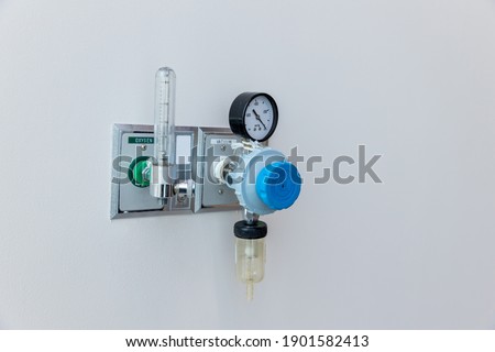 Oxygen flow meter plugged in the green outlet on hospital wall, Medical equipment. Oxygen for patients in the wall. Oxygen Gas Pipeline connection Inside Hospital ICU Room.