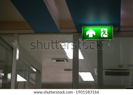 Security Concept, Green Emergency Fire Exit Sign in the Building. 