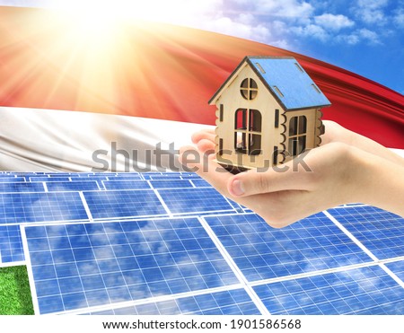 The photo with solar panels and a woman's palm holding a toy house shows the flag of Indonesia in the sun.