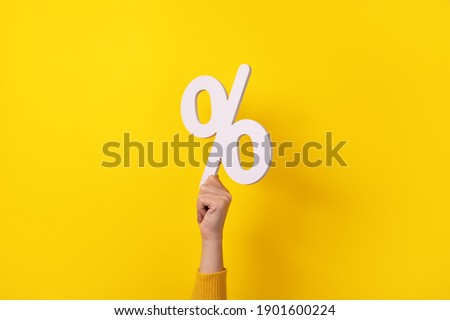 Woman hand holding 3D  white percentage sign over yellow background Royalty-Free Stock Photo #1901600224