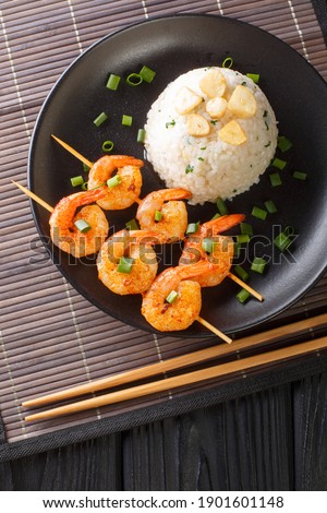 Japanese garlic rice served with fried shrimps close-up in a plate on the table.