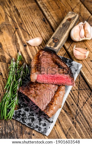 Grilled top sirloin cap beef meat steak on a cleaver. wooden background. Top view.
