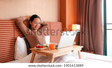Picture of tourists used laptop and eating fruits on the bed in the luxury hotel room, healthy food concept.