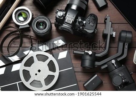 Flat lay composition with camera and video production equipment on brown wooden background