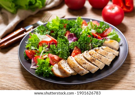plate of chicken salad with vegetables on wooden table