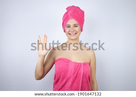 Young beautiful woman wearing shower towel after bath standing over isolated white background doing hand symbol