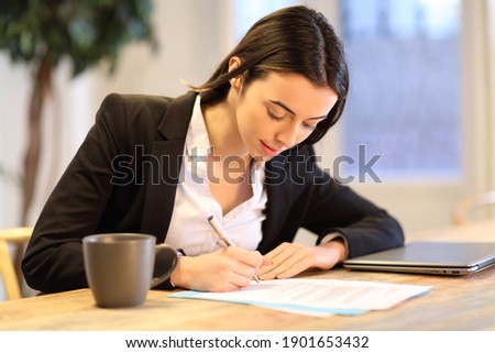 Happy businesswoman signing paper form working at office