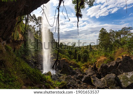 Photographer standing behind a waterfall, Sipi Falls, Uganda