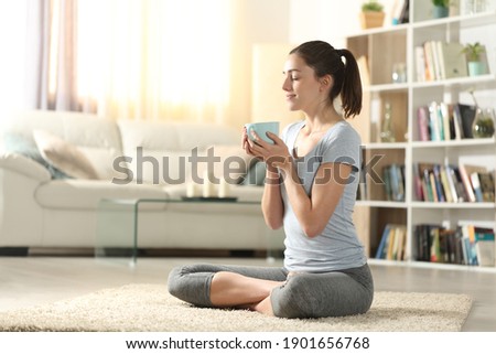 Yogi drinking tea after yoga exercises sitting on the floor at home Royalty-Free Stock Photo #1901656768