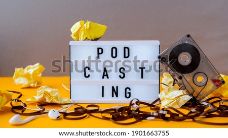 Podcasting lettering and audio cassette tape, headphones, crumpled paper in minimalistic isometric style. Trendy colors. Grey and yellow. Millenial. Blogger, podcaster. Audiobooks. New episode availab Royalty-Free Stock Photo #1901663755