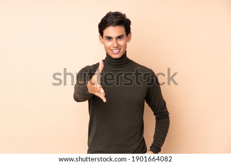Man over isolated background handshaking after good deal